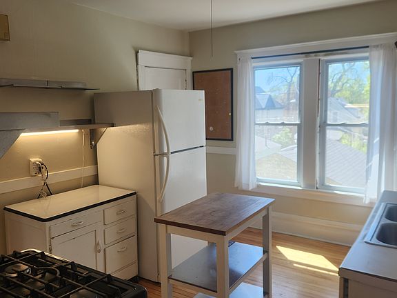 View into Kitchen from Bedroom. Kitchen includes island, cart, pantry, microwave, refrigerator and stove.