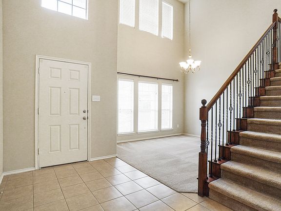 Beautiful stair case and ceramic tiled foyer and decorative lighting.