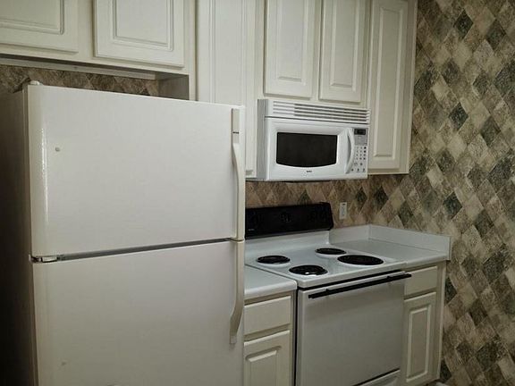 Kitchen includes an electric stove, refrigerator, microwave,