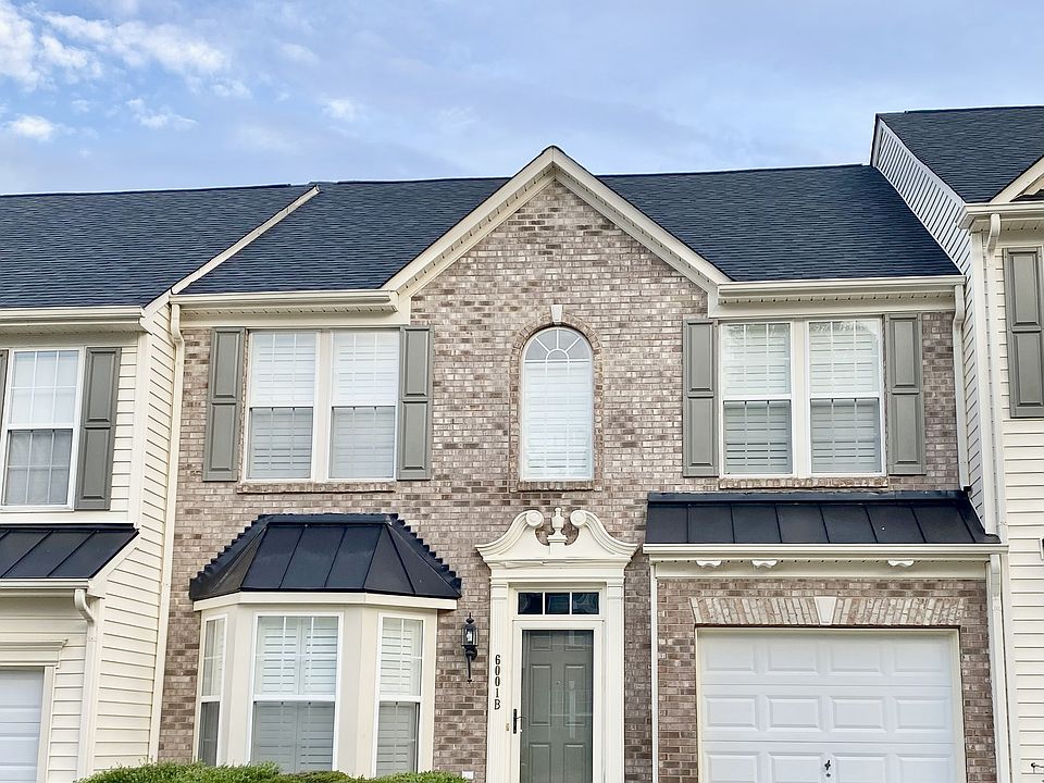 Elegant brick-front townhome with arched window, bay window, and decorative trim. Includes a 1-car garage, 2-car driveway, and neatly trimmed shrubs. Timeless curb appeal in a safe and well-kept community