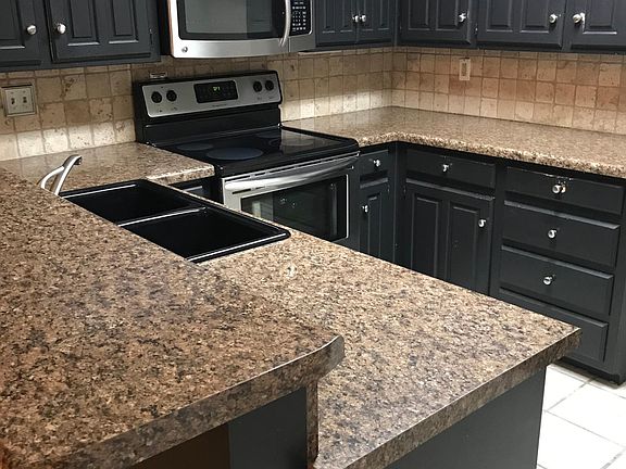 Built-In appliances include microwave and dishwasher. Electric Stove and plenty of cabinetry. Open concept into dining and living room. Also has garage entrance from a two-car garage. To the right is connections for your refrigerator and pantry closet.