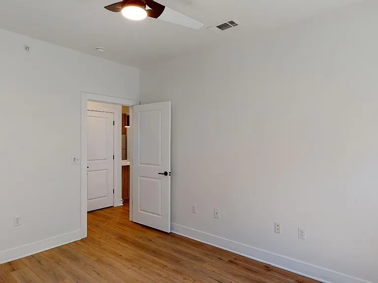 Spacious apartment bedroom with wood-style flooring.