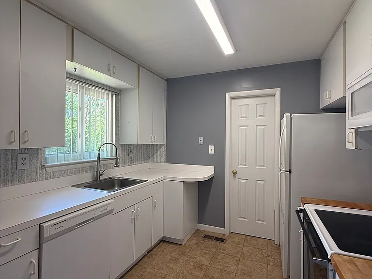 view from dining room into kitchen, door on the far end goes to utility room,
kitchen with dishwasher, stainless steel sink and window overlooking backyard