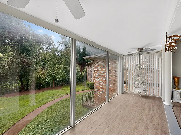 A spacious sunroom with ceiling fans on both ends, offering a comfortable space to enjoy the scenic outdoor view.