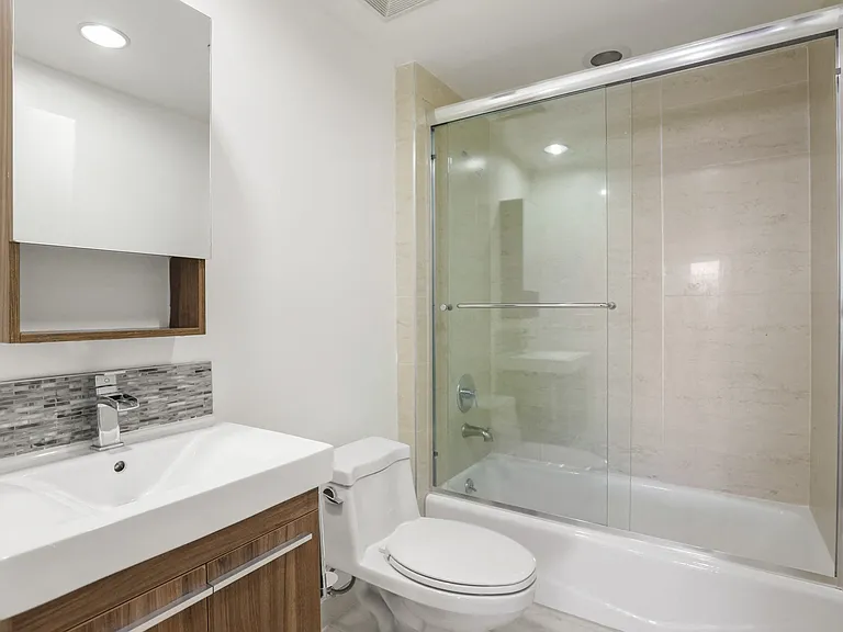Bathroom With Full-Size Bathtub and Glass Door