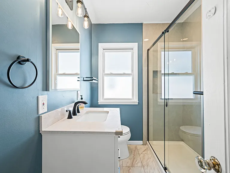 This is the updated bathroom on the second/main floor of the unit. It's located between the two bedrooms, and it includes a tile shower, medicine cabinet, and newer vanity.