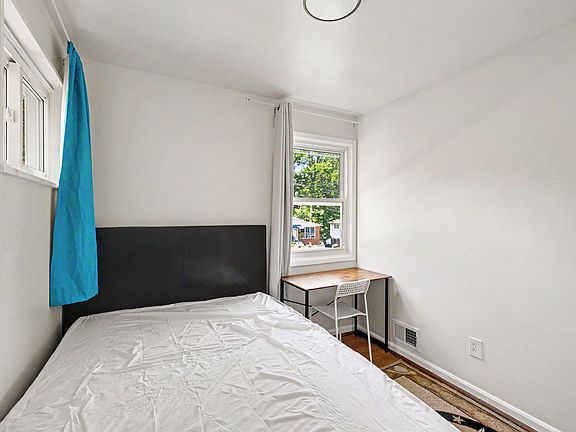 Private bedroom with a bed, dedicated desk area, and two windows that bring in natural light and outdoor views.