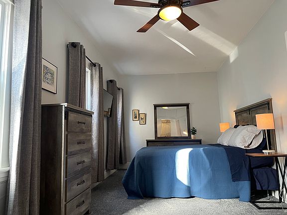 Primary bedroom. Featuring a queen bed, room blackening drapes, and ceiling fan.