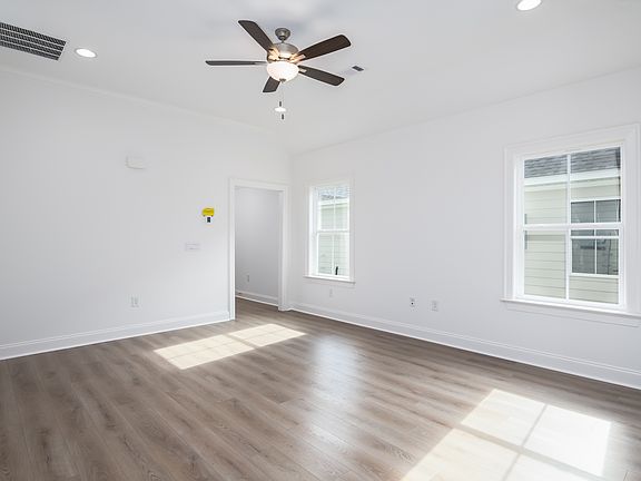 Spacious living room with large windows, wood-look flooring, and abundant natural light