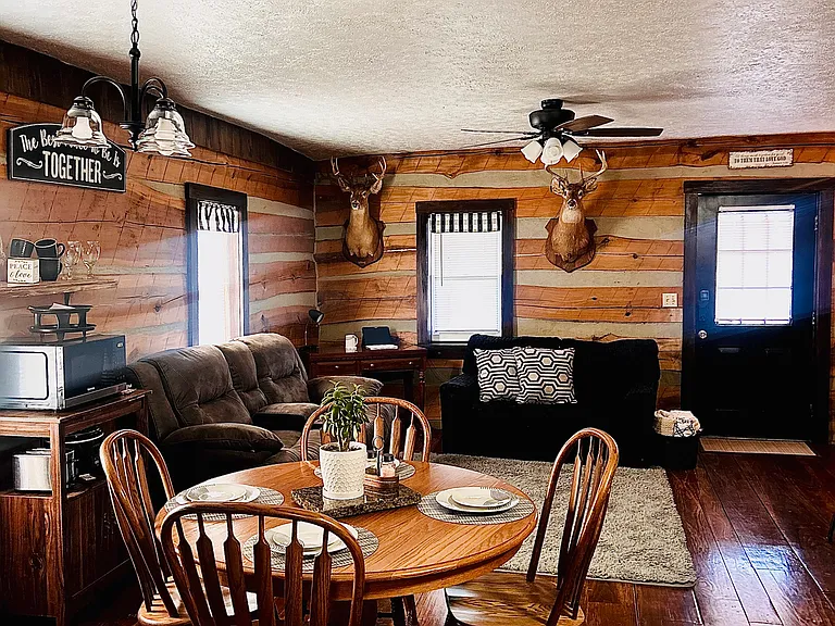 Bright, open living and dining space with warm wood-paneled walls, gleaming hardwood floors, and natural light pouring in
