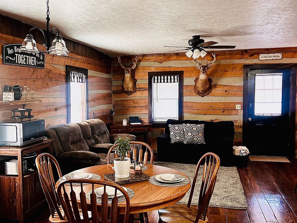 Bright, open living and dining space with warm wood-paneled walls, gleaming hardwood floors, and natural light pouring in