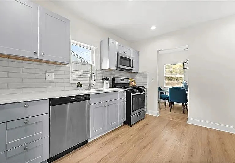 Updated kitchen with ample cabinetry, subway tile backsplash, and stainless appliances, opening to a dining area.