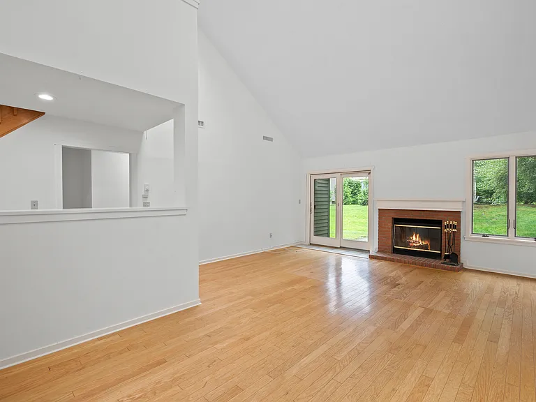 Living room with vaulted ceilings, dining area, large windows and skylights, and wood burning fireplace