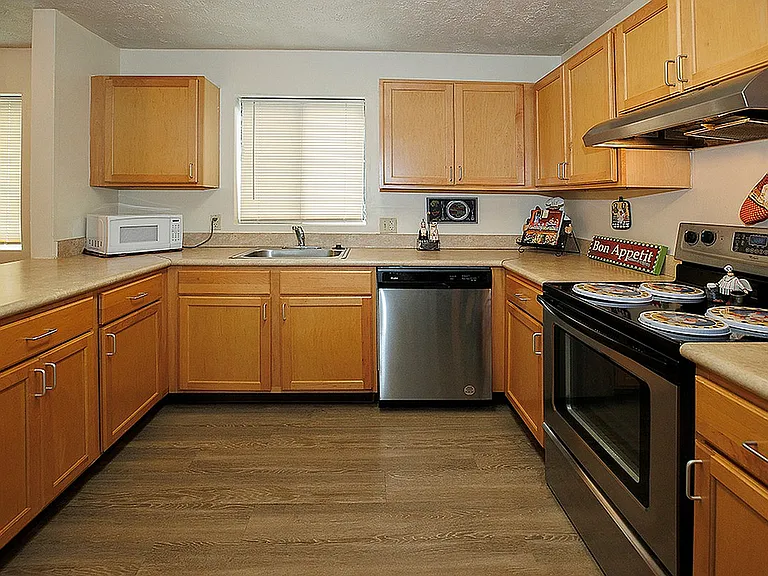 Inviting kitchen with warm wooden cabinets, stainless steel appliances, and sleek countertops.