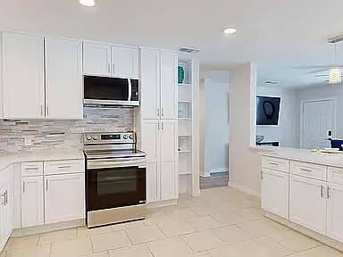 Open kitchen layout with built-in shelving, pantry storage, and clear sight lines to the living area