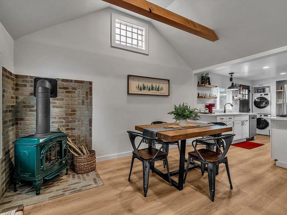 Open concept living & dining area featuring 55" Smart TV, gas fireplace, sectional seating and table for comfortable in home dining for 4. Entry area with bench & wall hooks for convenient shoe, coat & hat.