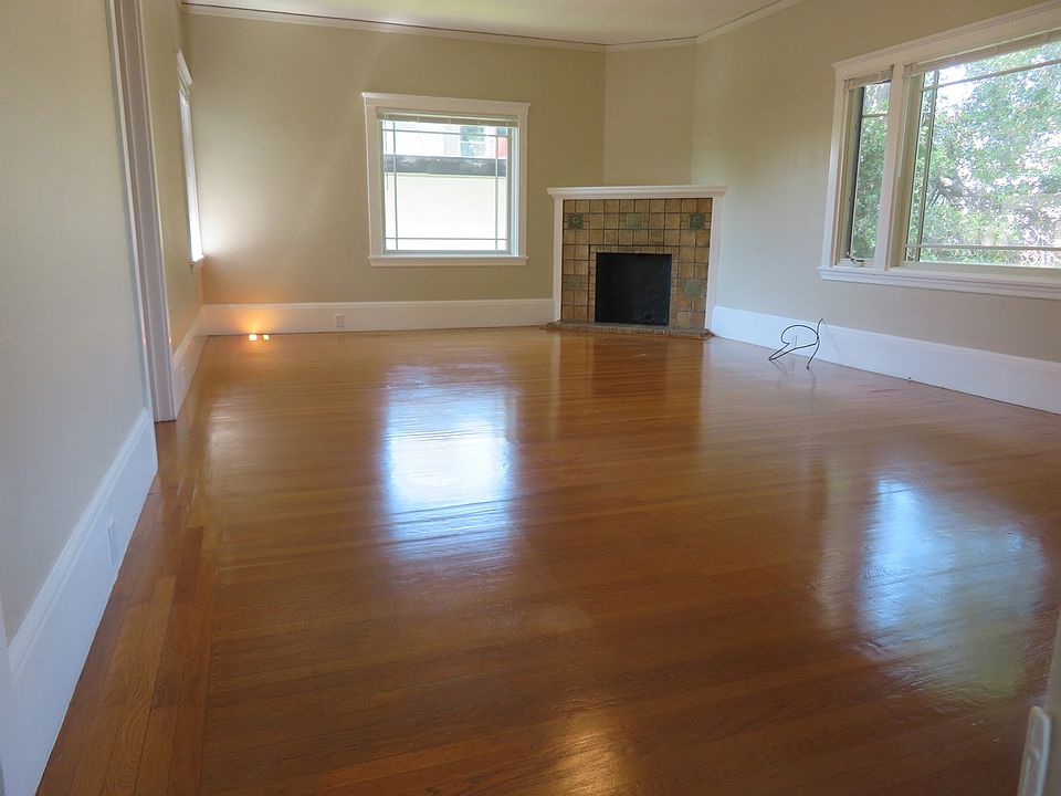 Living room with hardwood floors, high ceiling, large windows.