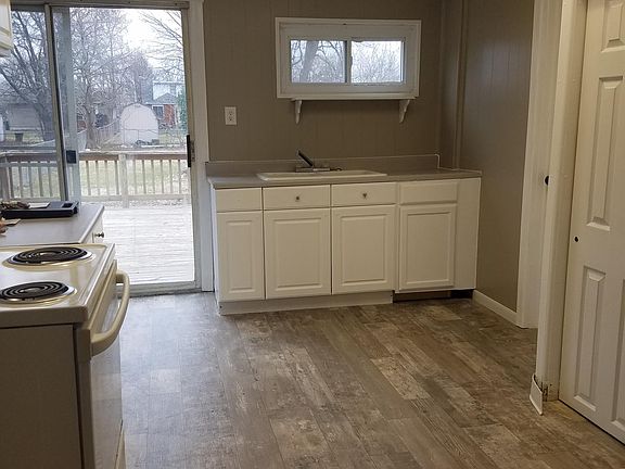 Kitchen with new flooring, stove, refrigerator, large pantry, freshly painted cabinets, sliding glass door to deck and backyard