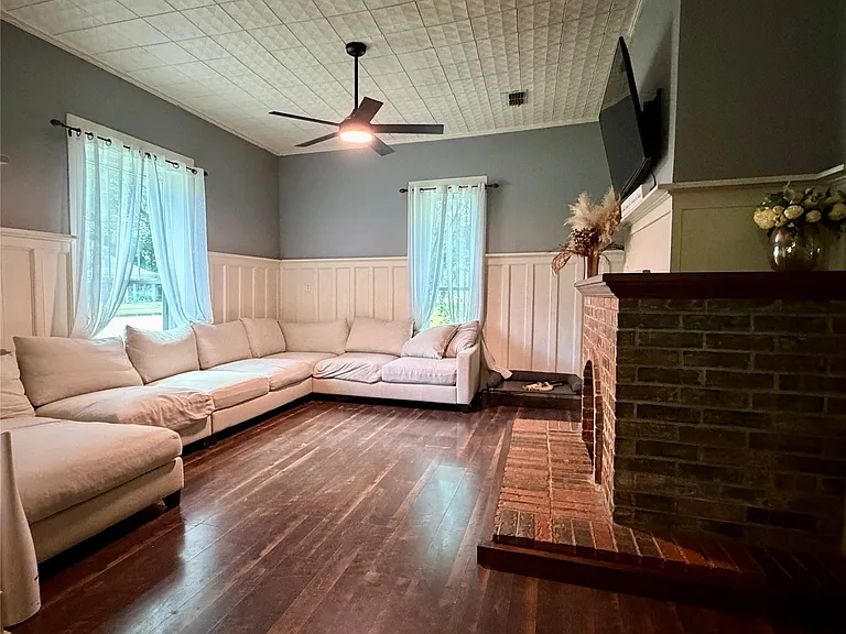 Living area featuring rich wood-finish flooring, textured ceiling, and a brick fireplace