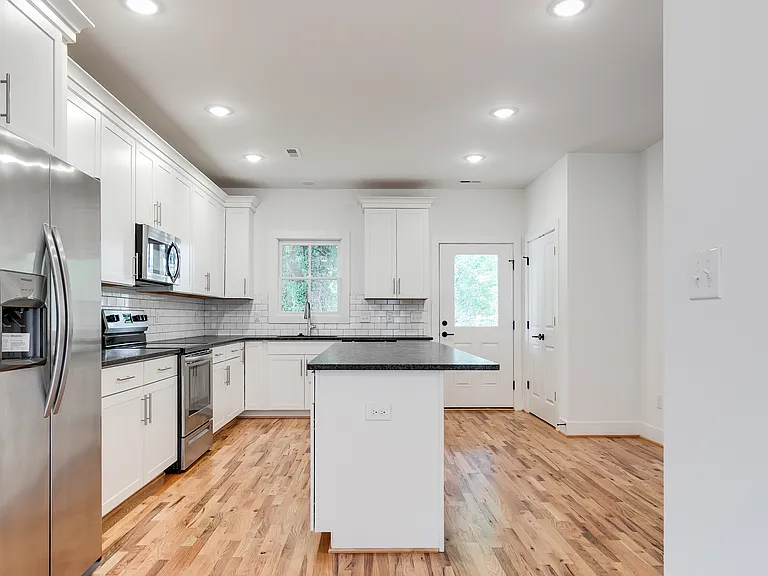 Kitchen with hardwood floors, recessed lights, pantry, island, stainless steel appliances, and access to backyard