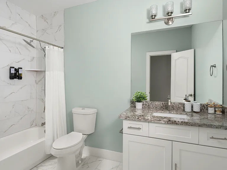 Shared hallway bathroom serving Bedrooms 1 and 2, featuring a tub/shower combo and granite vanity.