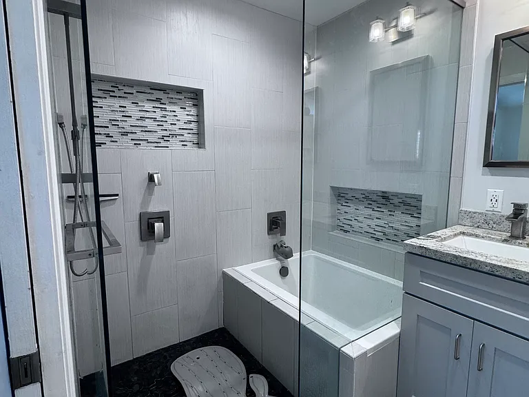 Combo soaker tub and shower with glass doors. The shower has multiple showering options.