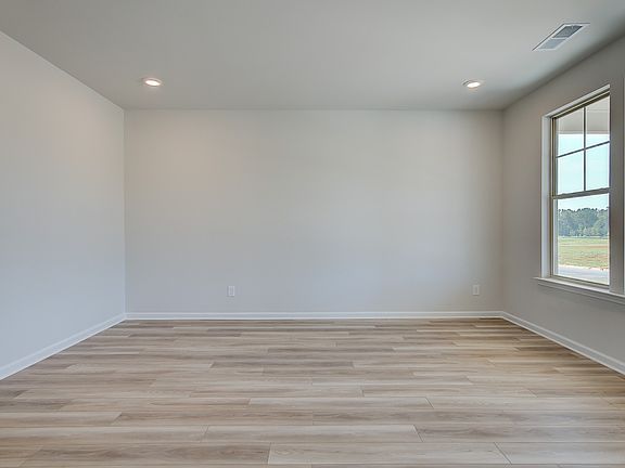 Bright living room with LVP flooring and large windows in the Clarity at Brighton in Locust Grove, G