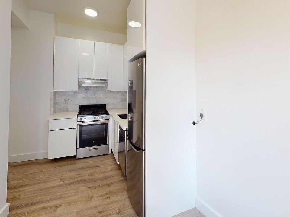 Modern kitchen with cabinets, stainless steel appliances, and wooden flooring. Bright, minimalist design with neutral tones, evoking a clean, airy feel.