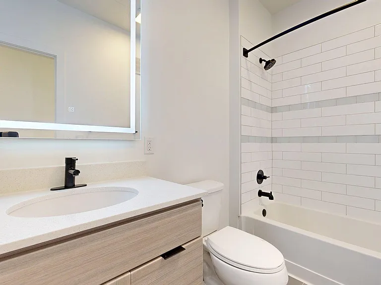 Apartment Bathroom with soaking tub, vanity mirror and tile floor.