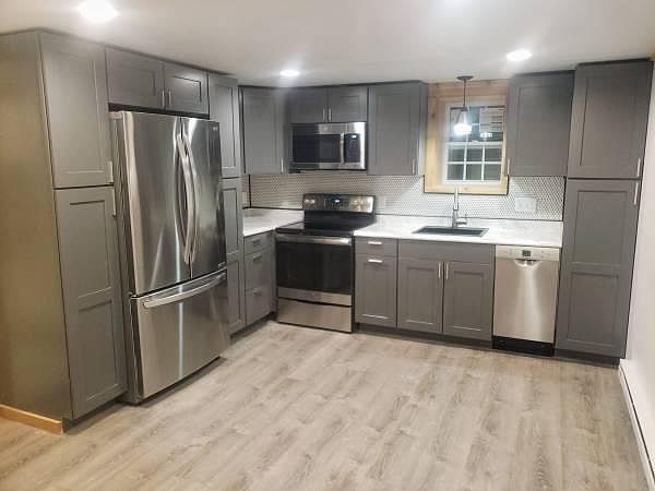 New stainless steel appliances, marble look countertop, tile backsplash, and loads of cabinet storage.