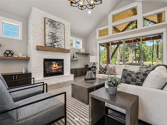 Relaxation and comfort await in great room with floor to ceiling modern white stone fireplace, built in cabinets and floating shelves