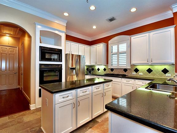Kitchen has granite counters, under and over cabinet lighting, decorative tile backsplash, and recent stone tile floors.