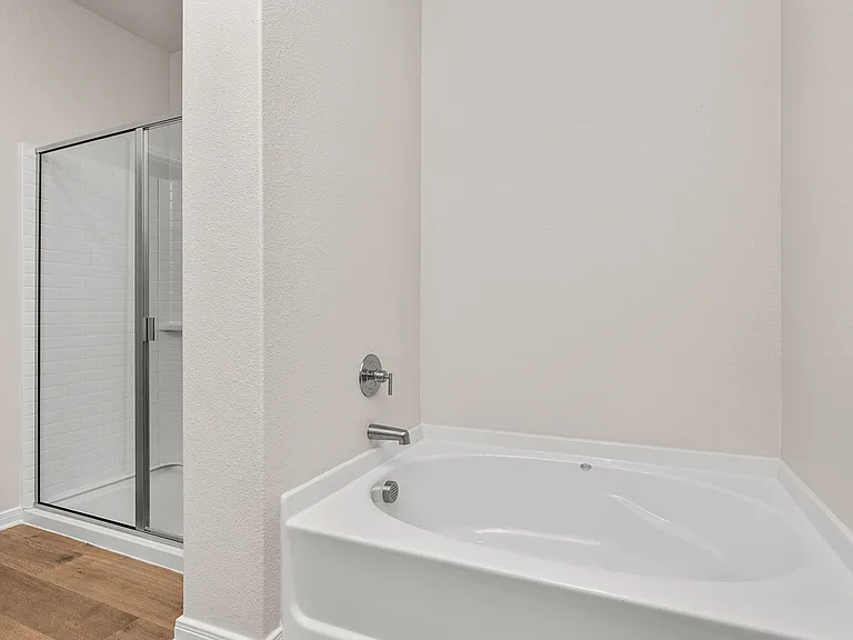 The master bathroom has a garden tub and glass, walk-in shower.