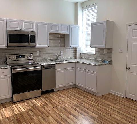 Kitchen Area with Stainless Steel Appliances; Refrigerator, Range/Oven; Microwave, Dishwasher; Sink/Garbage Disposal; Porcelain Tile Back Splash; White Cabinets; LED Dimmer Controlled Ceiling Lighting; Laminated Hardwood Flooring -Right Side View