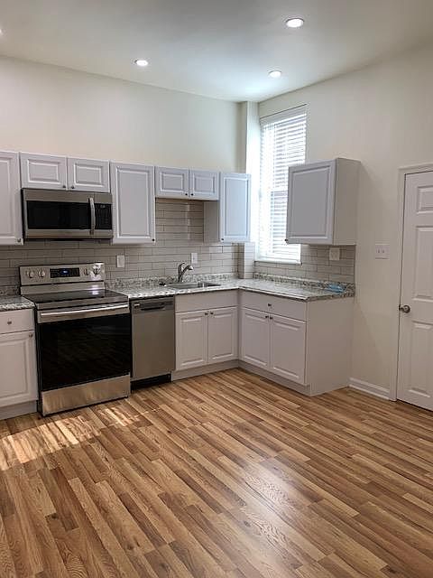 Kitchen Area with Stainless Steel Appliances; Refrigerator, Range/Oven; Microwave, Dishwasher; Sink/Garbage Disposal; Porcelain Tile Back Splash; White Cabinets; LED Dimmer Controlled Ceiling Lighting; Laminated Hardwood Flooring -Right Side View