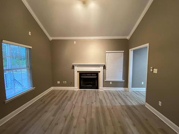Living room with high vaulted ceiling and gas ventless fireplace. ~350 sqft covered front porch off of this space.