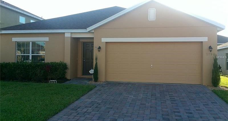 Exterior of front with paver drive and luscious yard.