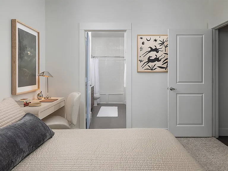 Spacious apartment bedroom with a large closet, attached bathroom, and plush carpet flooring.