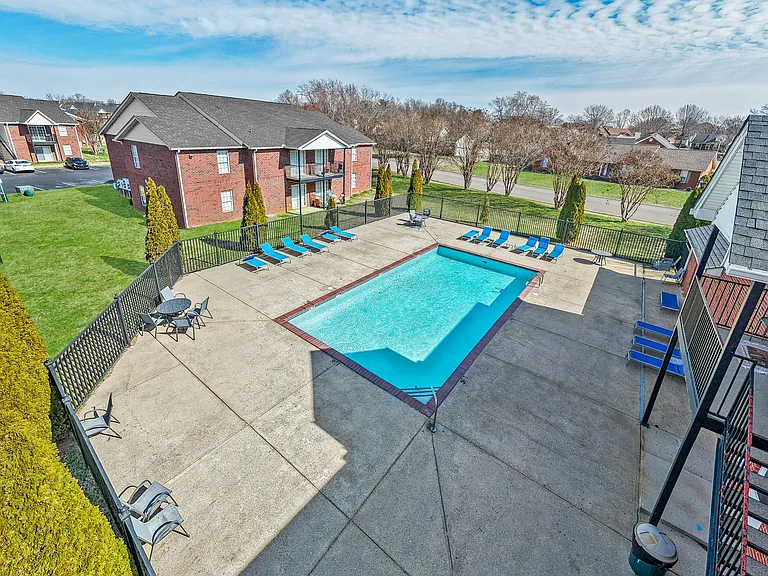A swimming pool surrounded by large sundeck with lounge chairs.
