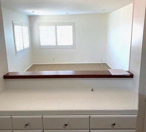 Adequate kitchen counter and storage space with mahogany counter for serving. Looking from the kitchen into the front room. All windows in this unit have shutter treatment.