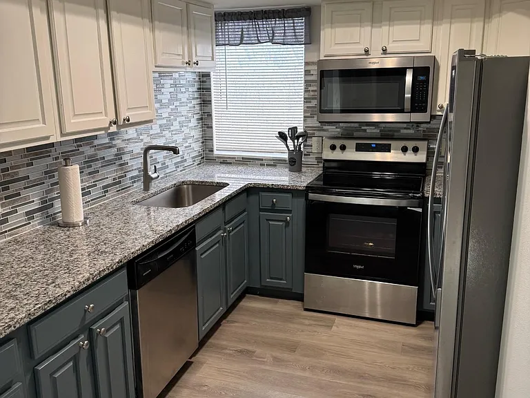 Efficient U-shaped kitchen with ample cabinet storage, granite counters, and stainless steel appliances plus a window over si