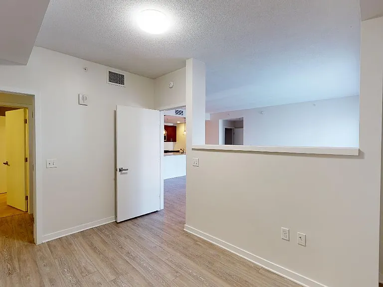 Spacious apartment bedroom with wood-style flooring.