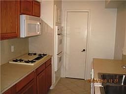 Kitchen has tile floors, microwave, cooktop stove, double ovens and a breakfast bar to the den.