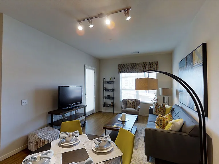 Apartment living room with wood-style flooring and balcony and patio in select homes.