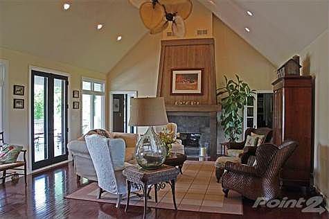 The great room w/ hardwood floors, twin paddle fans, a see through gas fireplace and views of the pond.