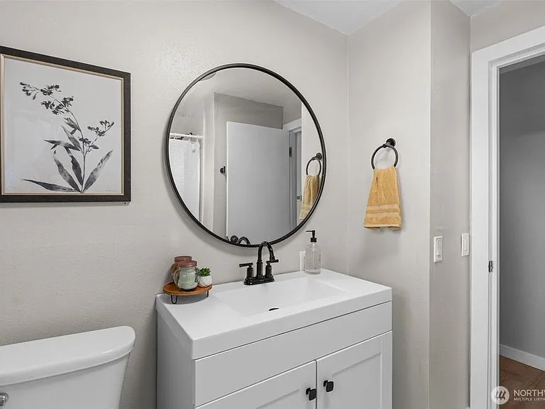 Updated bathroom vanity with ample cabinet storage, round mirror, and easy access to the shower area.