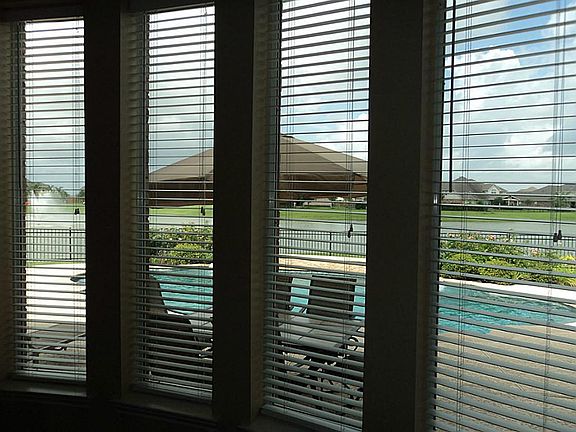 Floor to ceiling windows look out over pool area and beyond across lake front and fountain