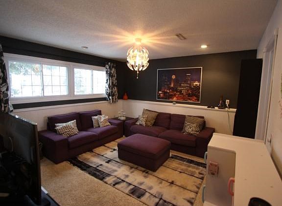 Family room with 4 window's white trim, and wainscoting make this room look like it's from a magazine.