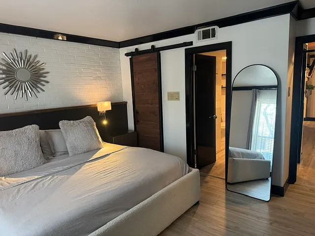 Walk-in closet is behind the beautiful barn door. You can catch a glimpse of the adjoining bathroom.