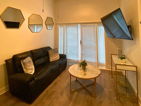 Living area features a 2-seat sofa, decorative mirrors, coffee table, and Smart TV.